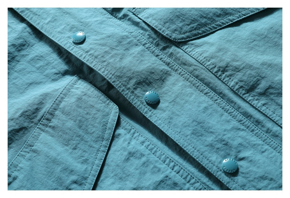 Close-up of a teal jacket's snap-button placket and stitched pocket flaps.