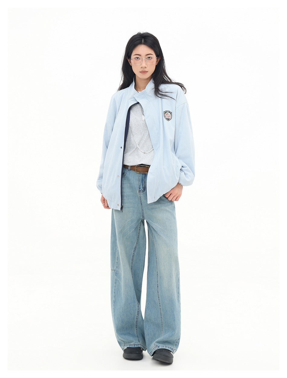 Full-length model wearing a pale blue jacket with a raised collar and chest crest, wide-leg jeans, and black shoes.
