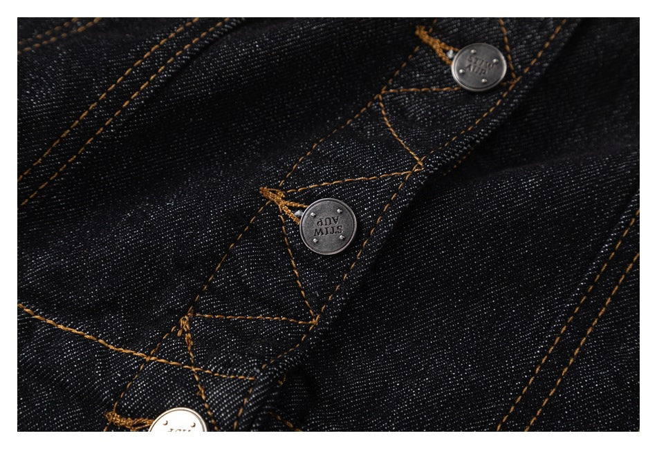 Close-up of metal buttons and orange topstitching on black denim.