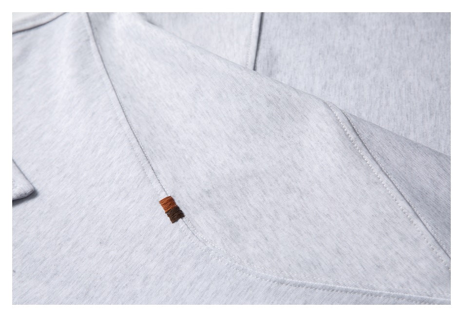 Light gray garment seam with a small brown stitched accent.