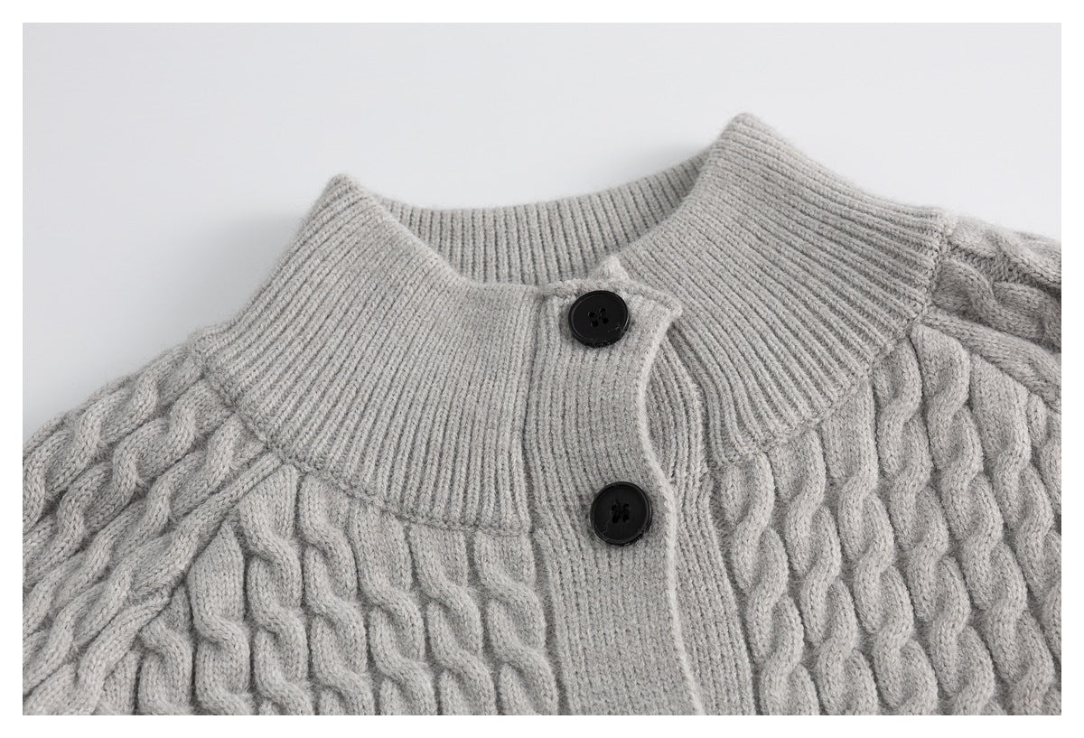 Close-up of a light gray cable-knit cardigan with a ribbed collar and black buttons.