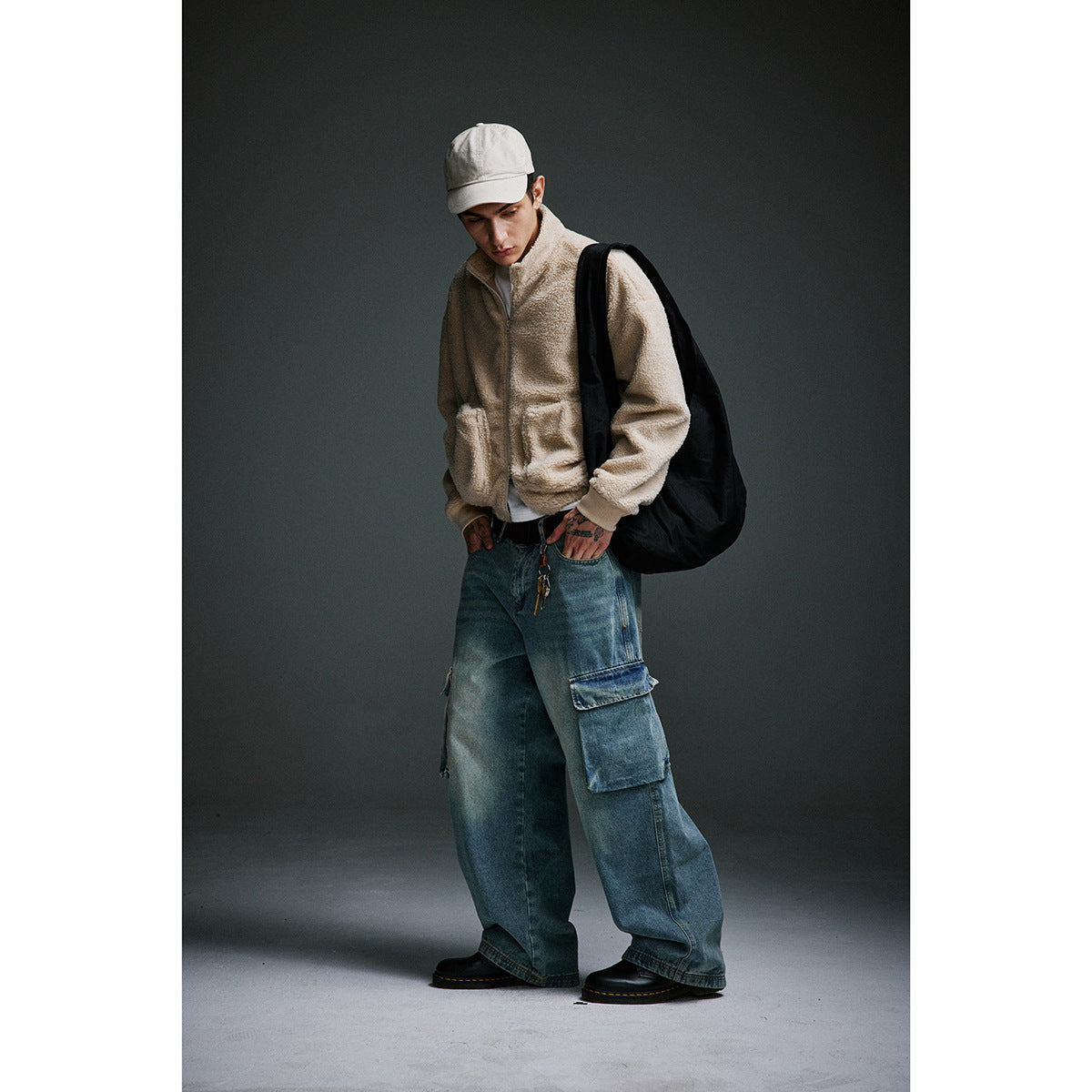 Model wearing a beige zip-up fleece jacket with patch pockets and loose blue cargo jeans.