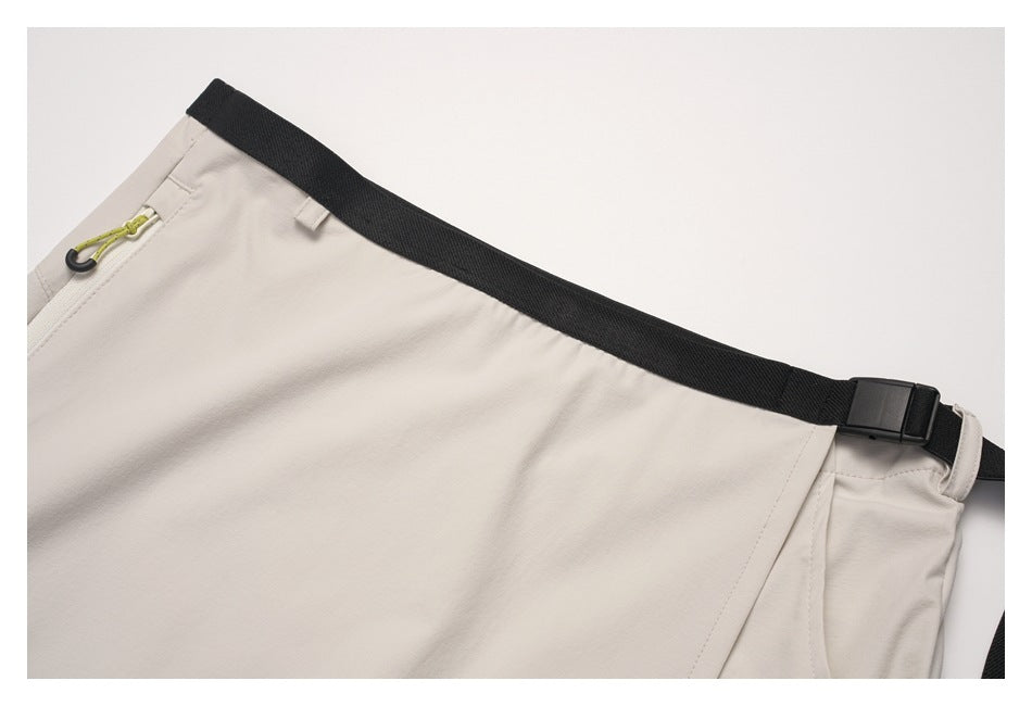 Close-up of the beige skirt's black adjustable waist strap, buckle, belt loop, and small zip pocket.