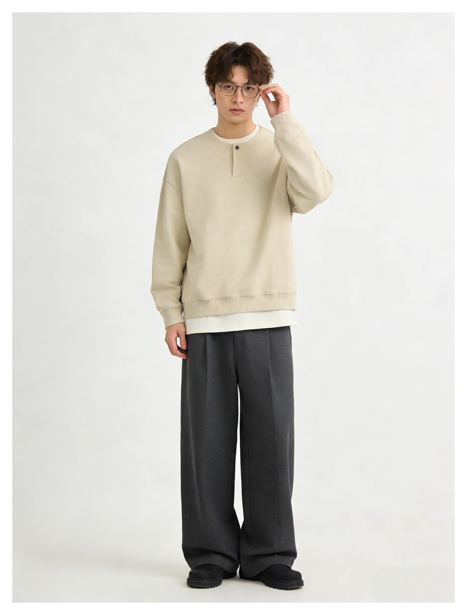 Full-length model wearing a cream oversized sweatshirt with a button placket and dark wide-leg trousers.