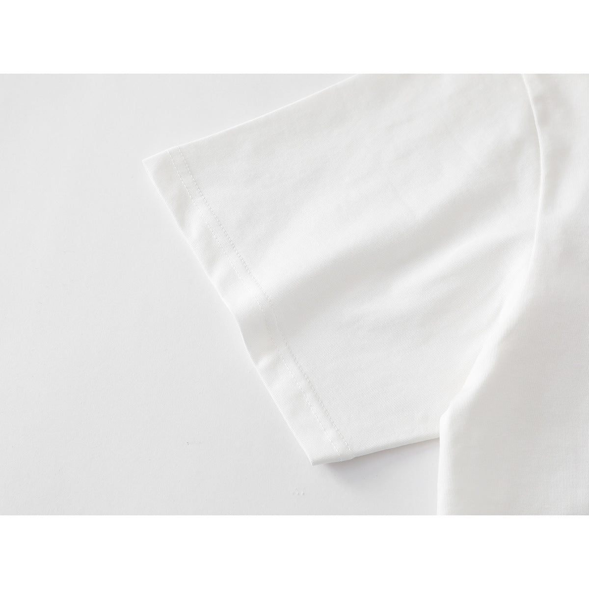 Close-up of the plain white T-shirt's short sleeve and stitched hem.