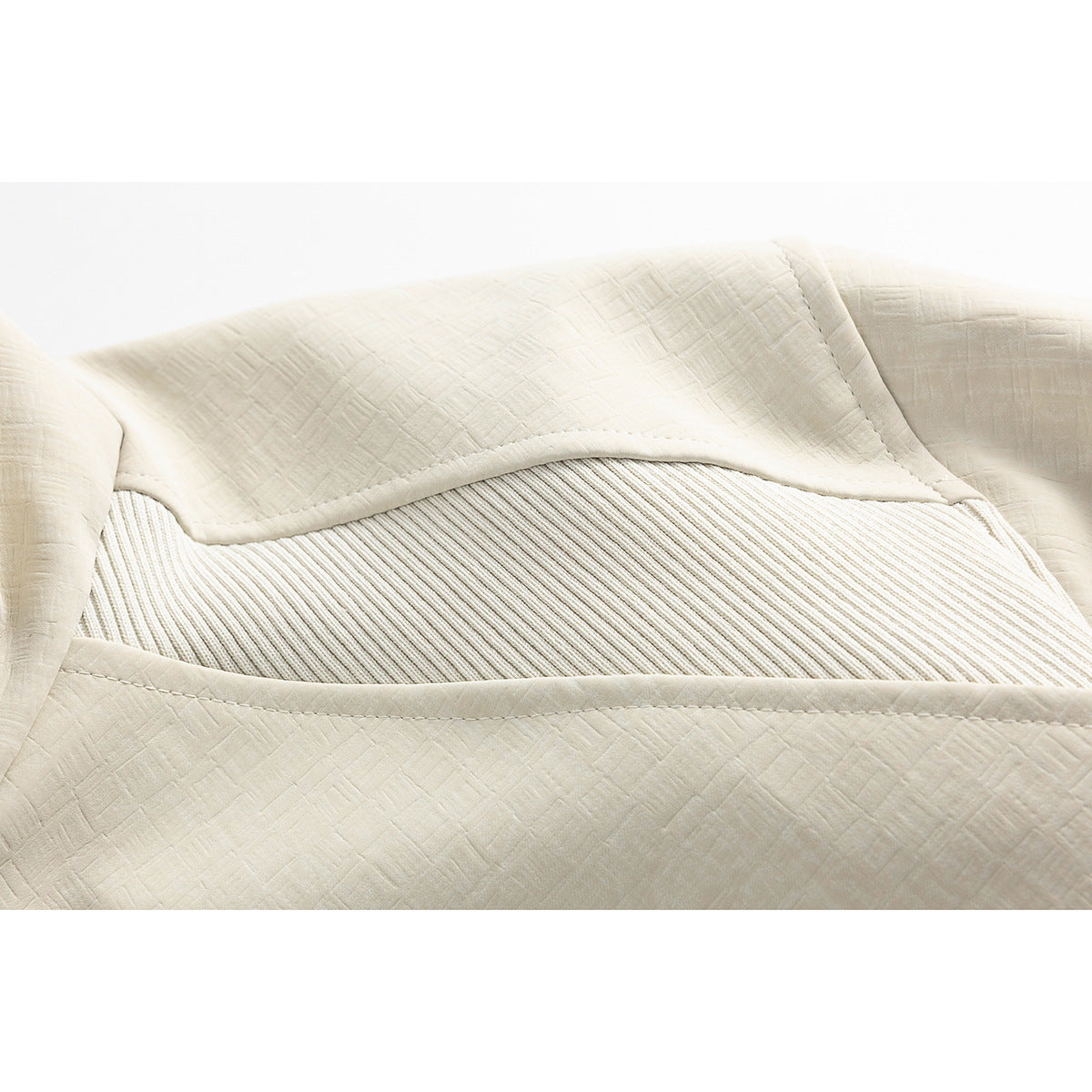 Close-up of an ivory jacket's ribbed shoulder insert and textured fabric panels.