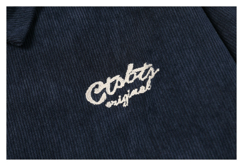 Close-up of small white script embroidery on dark navy ribbed fabric.