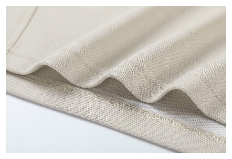 Close-up of stitching and an overlocked seam along the hem of a light beige garment.