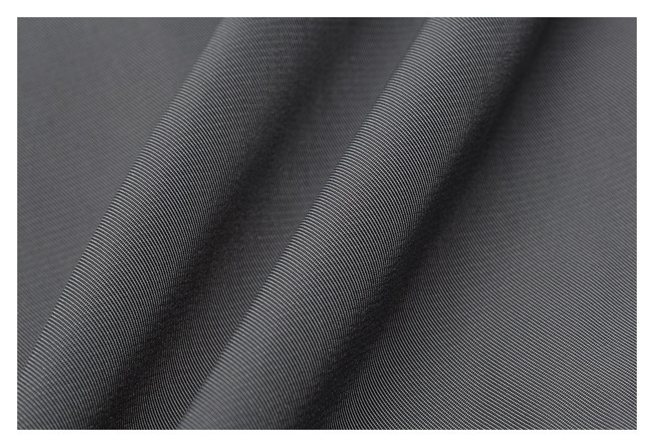 Close-up of dark gray fabric with a fine diagonal weave and soft folds.
