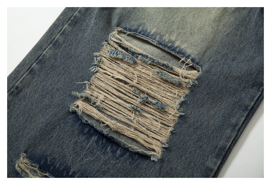 Close-up of a large frayed horizontal rip in faded blue denim.