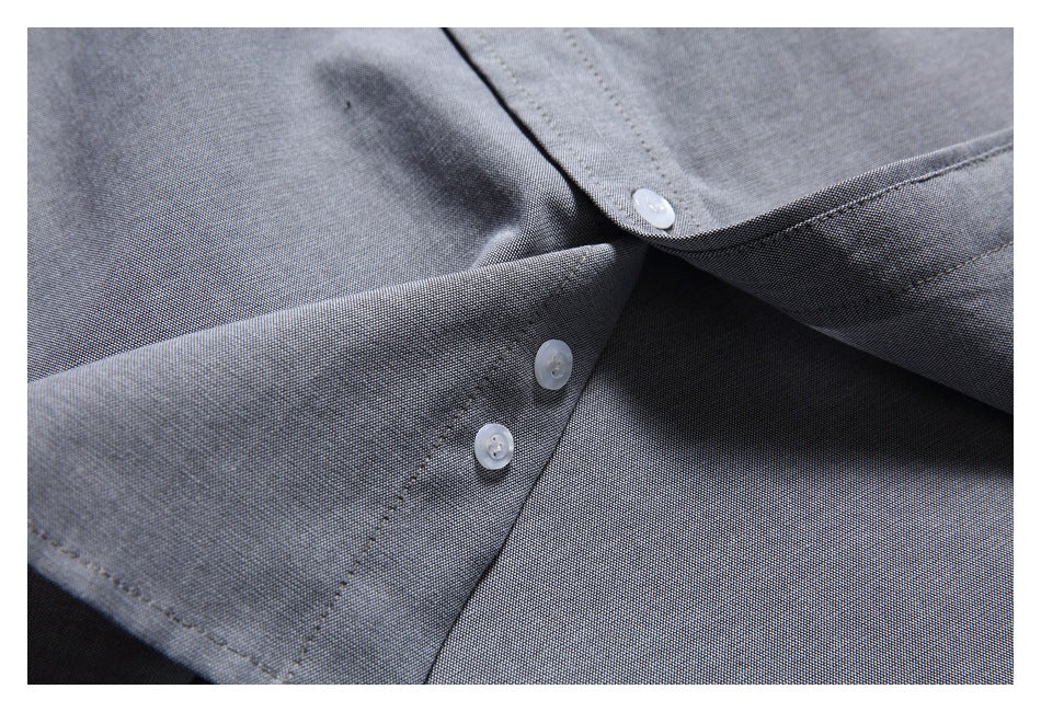 Close-up of the gray shirt's curved hem and buttoned front placket.