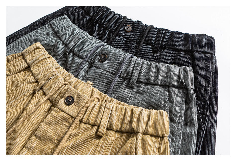 Close-up of three pants waistbands in black, gray, and tan, showing buttons, belt loops, and a ribbed texture.