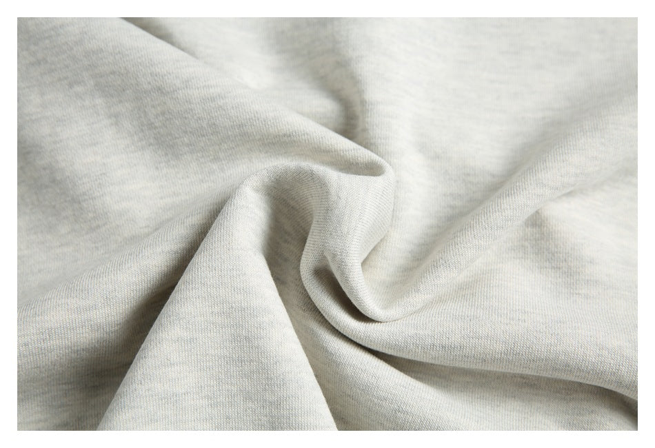 Close-up of light gray knit fabric gathered into soft folds, showing its surface texture.