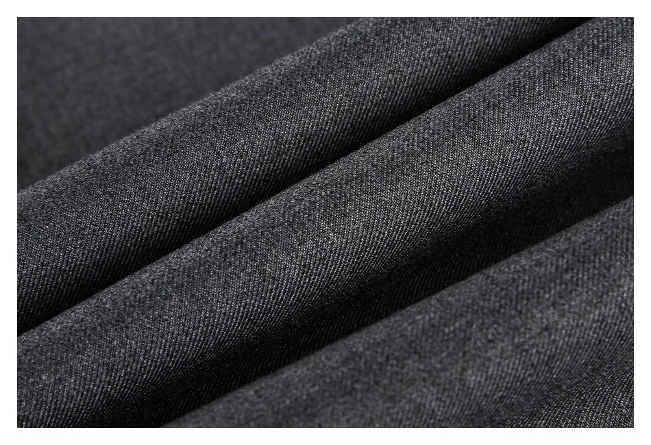 Close-up of dark charcoal gray fabric folded into soft diagonal ridges, showing a fine woven texture.