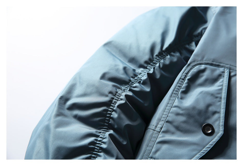 Close-up of the blue jacket's gathered sleeve seam and buttoned flap pocket.