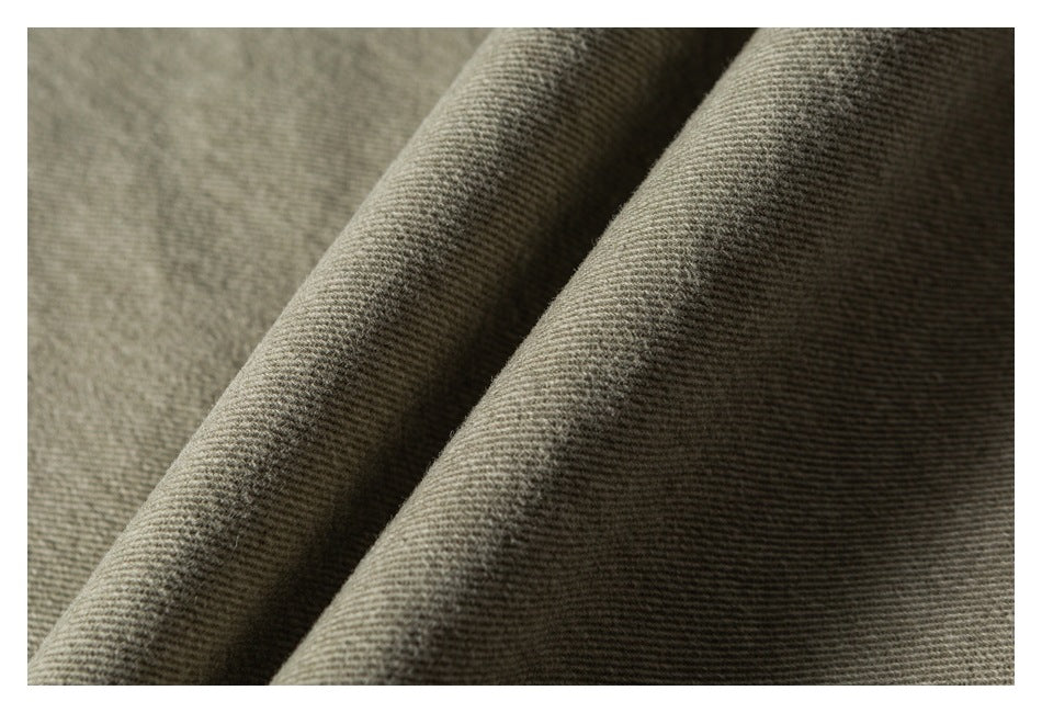 Close-up of olive-gray fabric draped in folds, showing its fine diagonal weave.