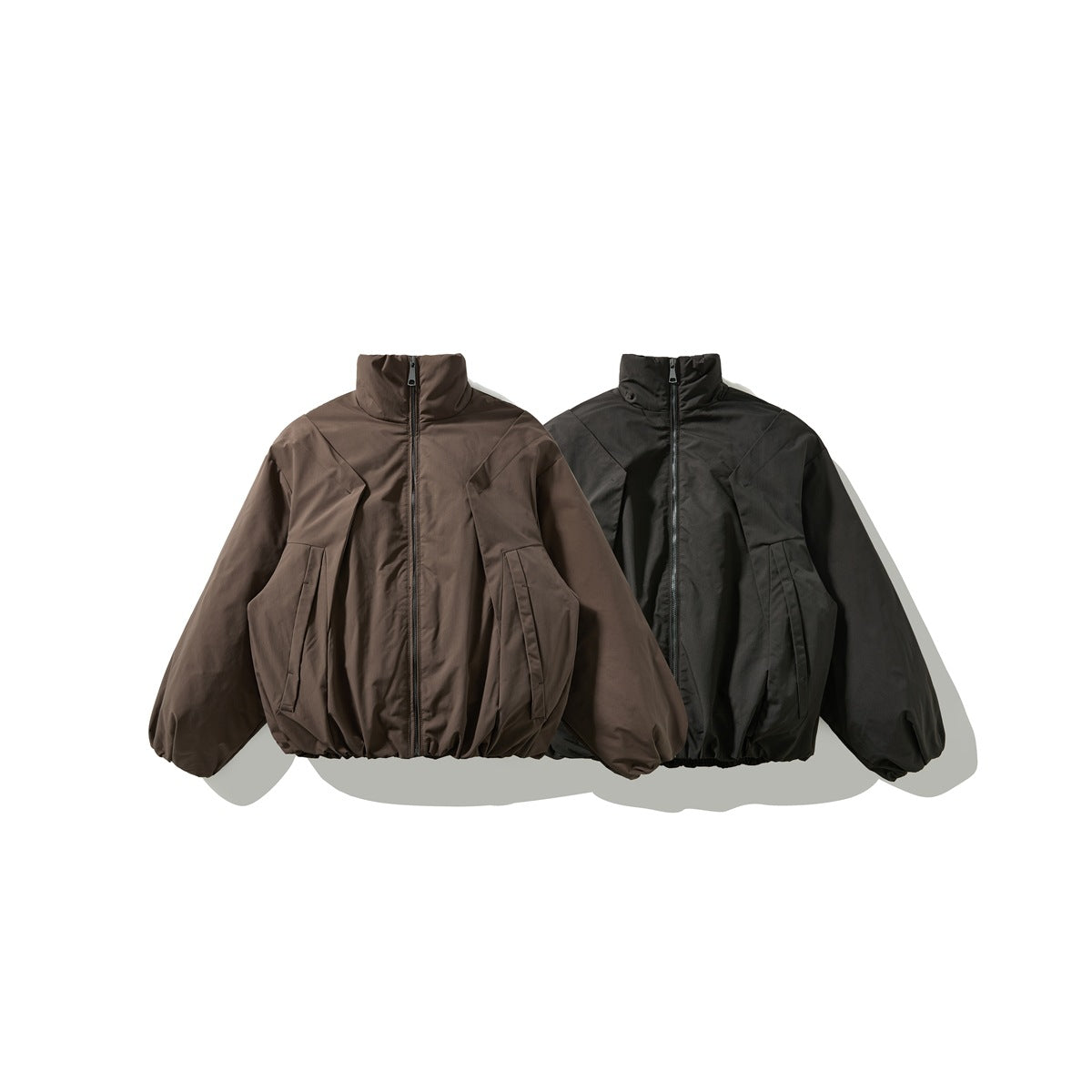 Front view of two high-collar zip jackets, one brown and one black, with roomy sleeves and front pockets.
