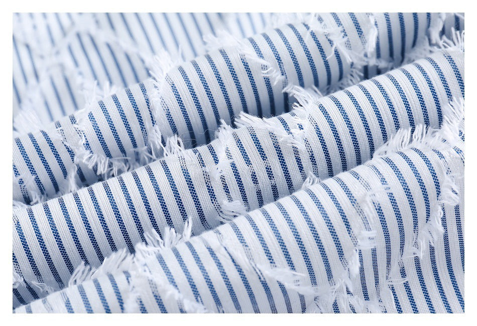 Macro view of gathered blue-and-white striped fabric with prominent frayed cutout details.
