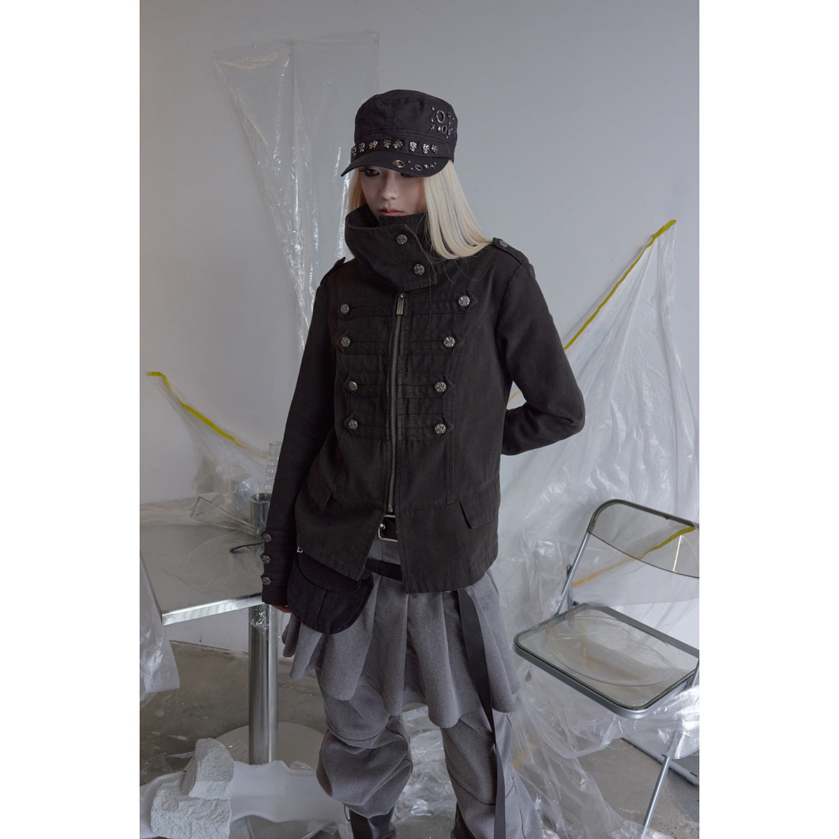 A model wears a black zip-front jacket with a high stand collar and decorative buttons, paired with gray layers.