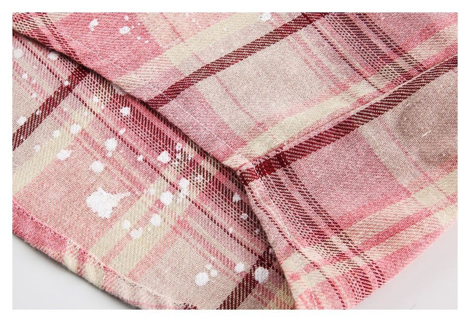 Close-up of intersecting seams on pink plaid fabric with scattered white marks.