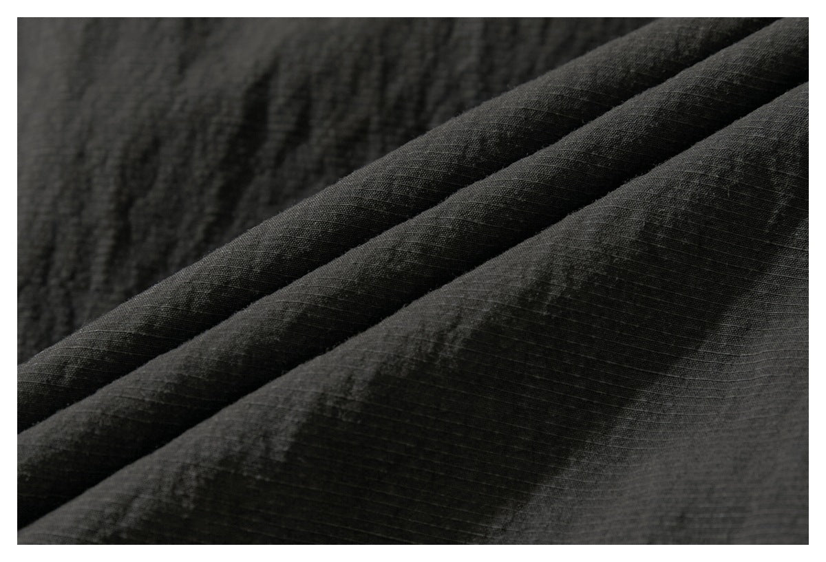 Macro view of dark charcoal fabric folded into ridges, showing its subtle grid-like texture.