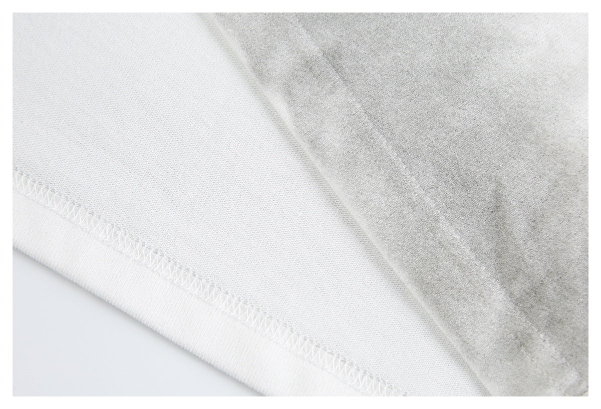 Close-up of an off-white shirt's stitched hem and fabric folded back to show the underside.