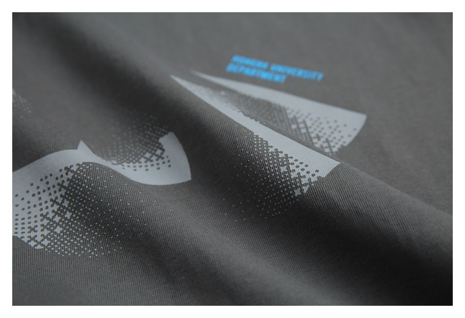 Close-up of a pale geometric print and small blue lettering on charcoal fabric.