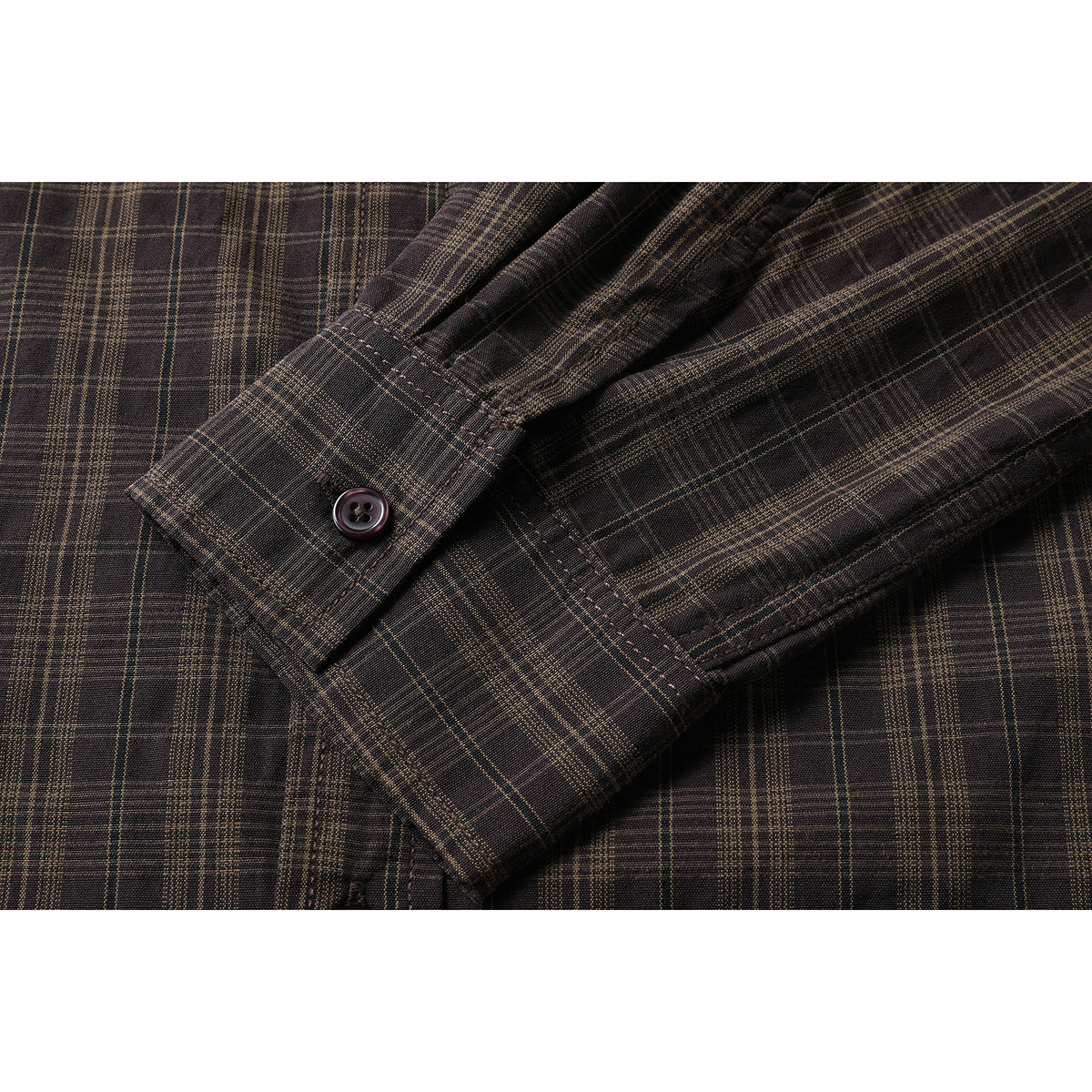 Close-up of the dark brown plaid shirt's long sleeve and button cuff.