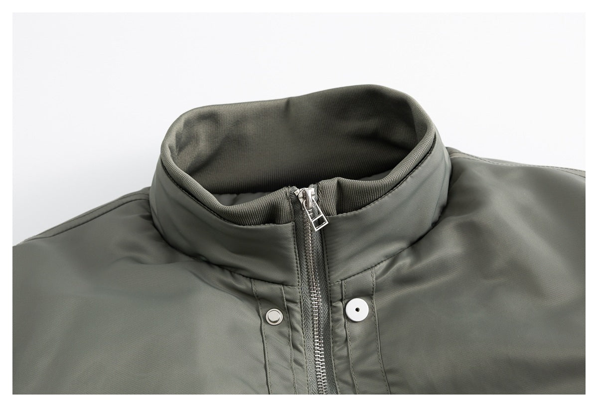 Close-up of an olive-gray jacket’s raised collar, front zipper, and snap-button placket.