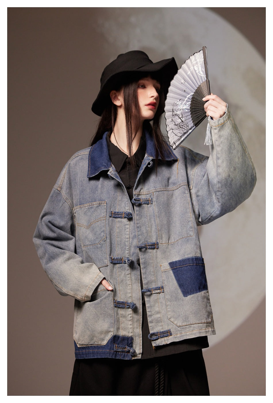 Close view of a model wearing a gray denim jacket with dark blue panels and large patch pockets.