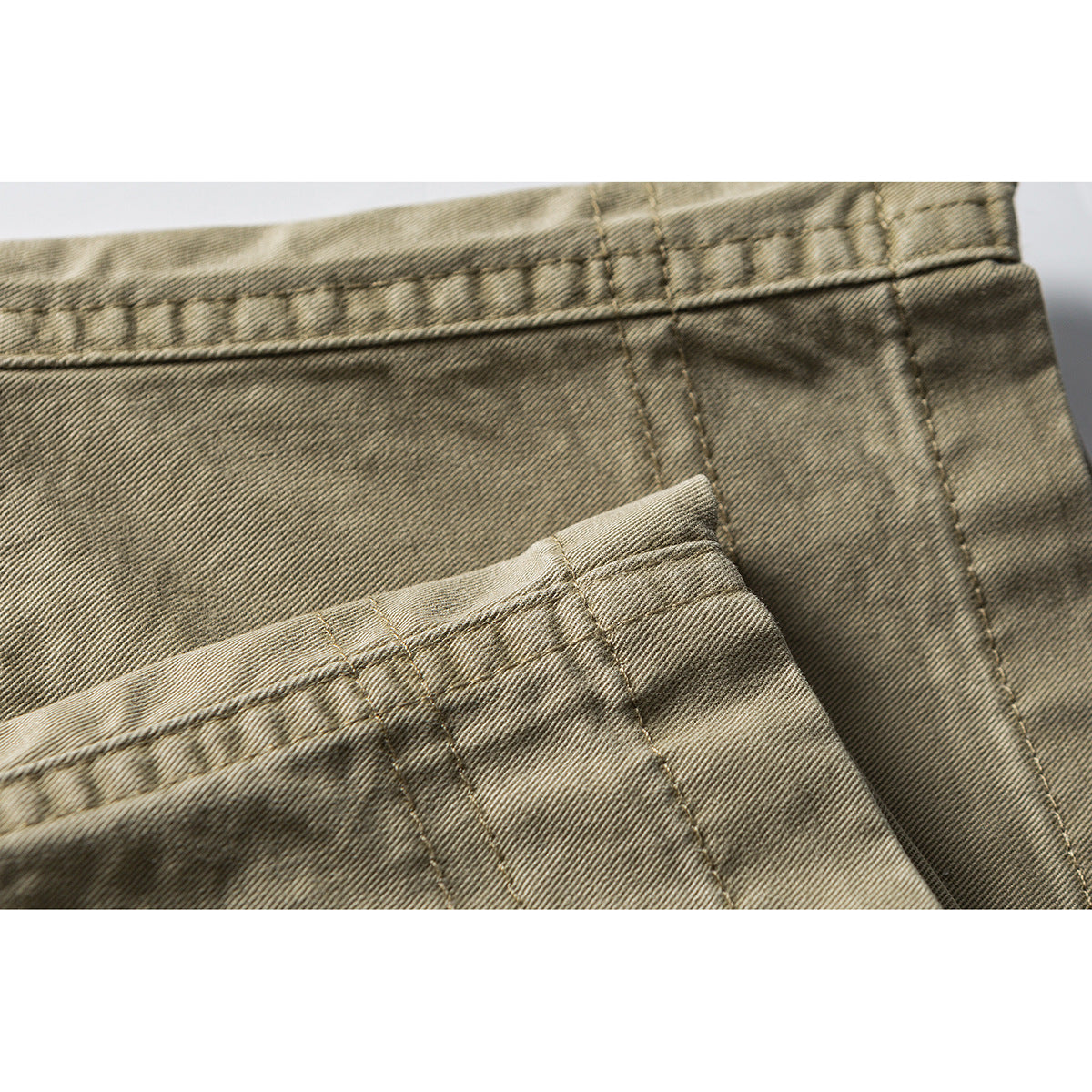 Close-up of khaki shorts showing the waistband, stitching, and overlapping fabric panels.