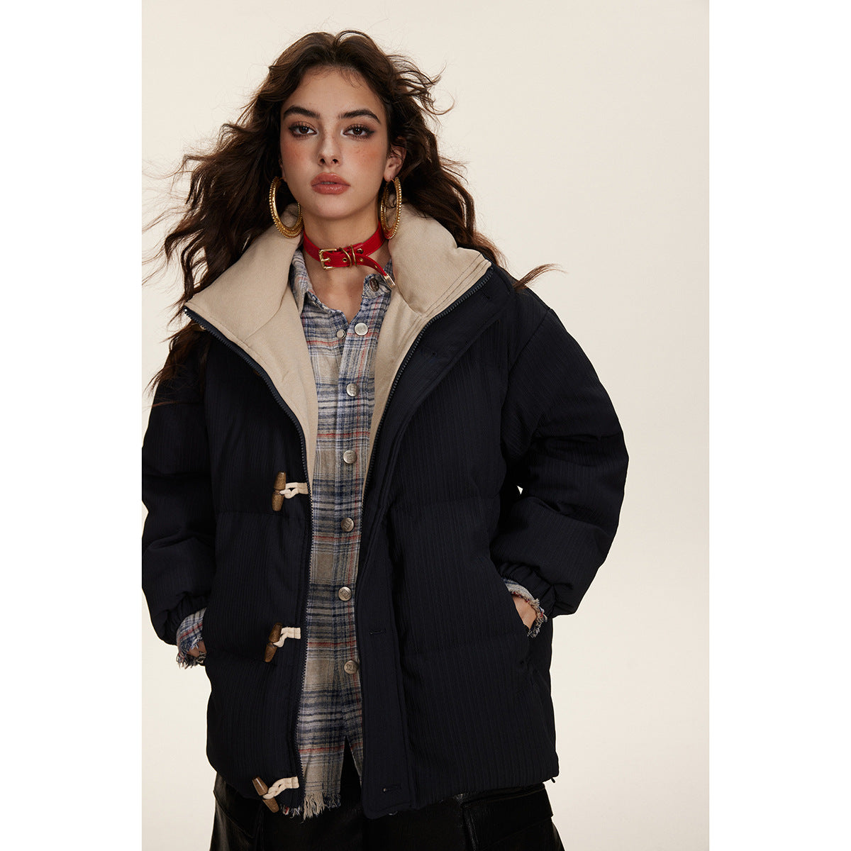 Model wearing an open dark padded jacket with a beige lining and high collar.