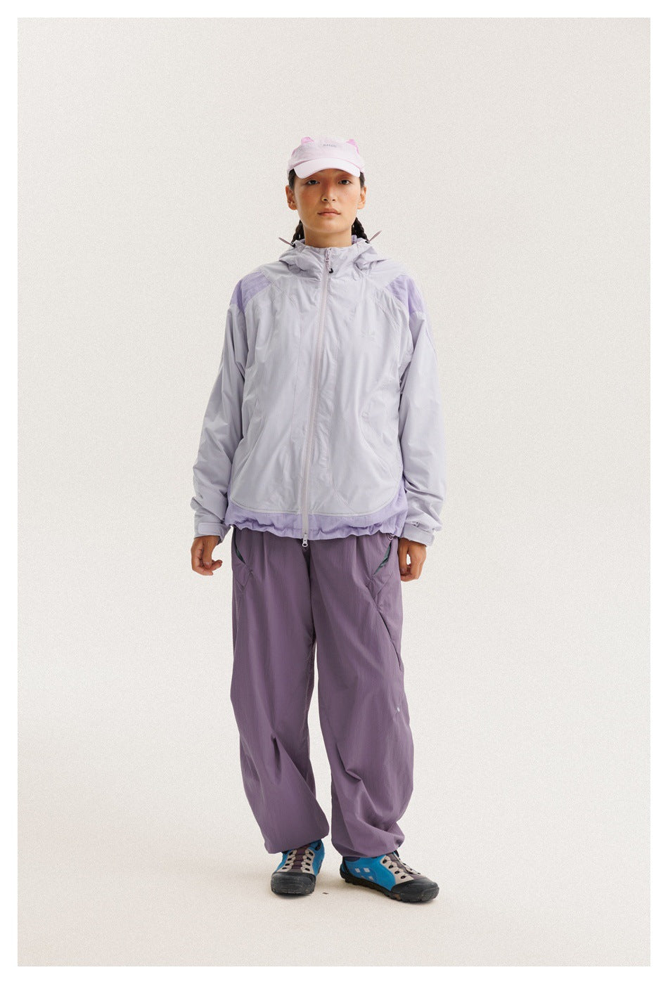 Front view of a model wearing a pale lavender hooded zip jacket and loose purple pants.