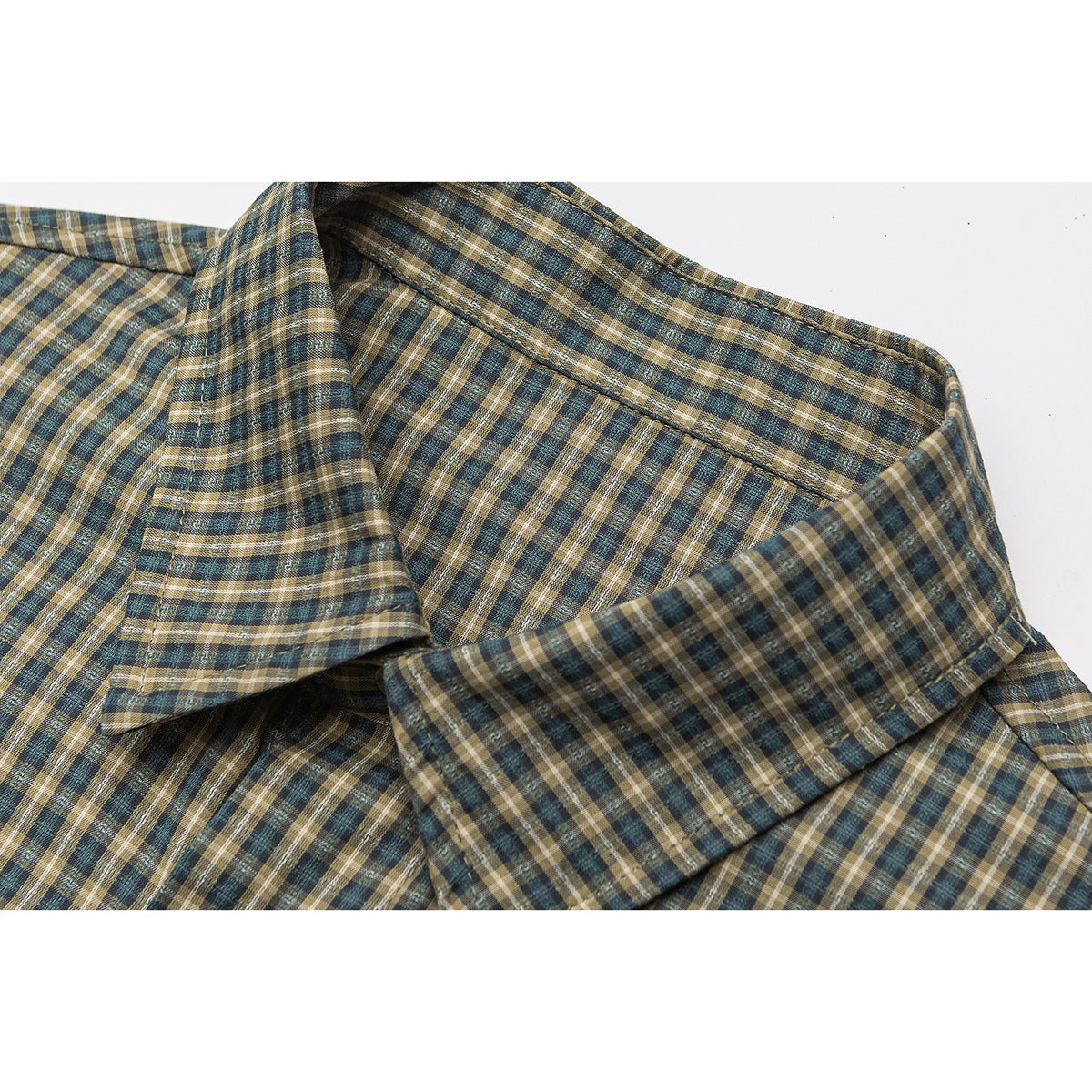 Close-up of a pointed collar on a teal, brown, and cream plaid shirt.