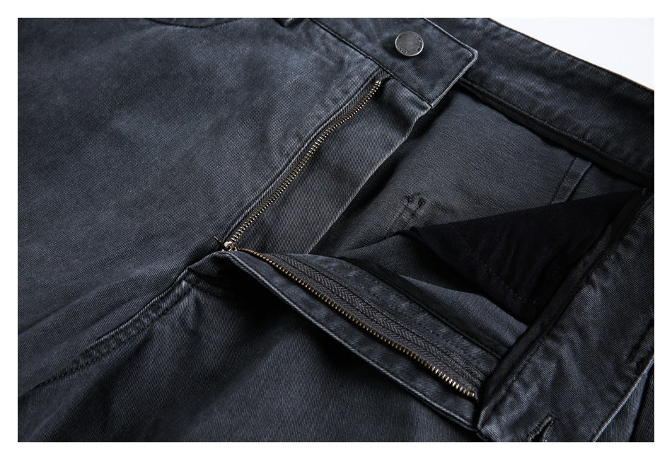 Close-up of dark charcoal jeans with the waistband button and open front zipper fly.