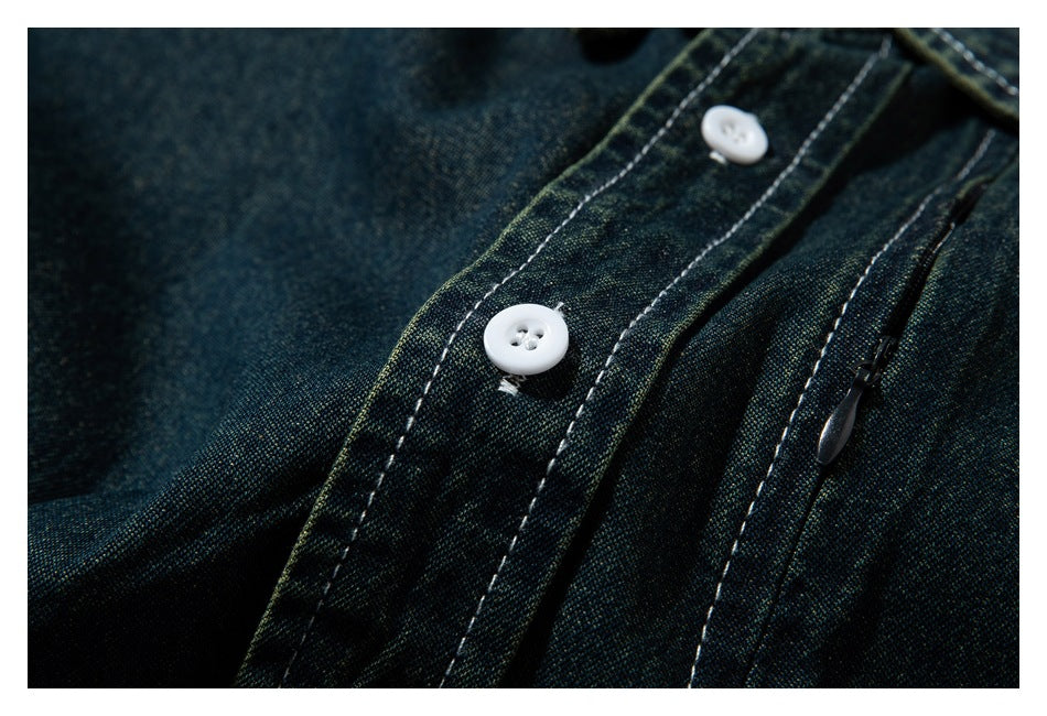 Close-up of dark indigo-green garment fabric with white stitching, two white buttons, and a zipper.