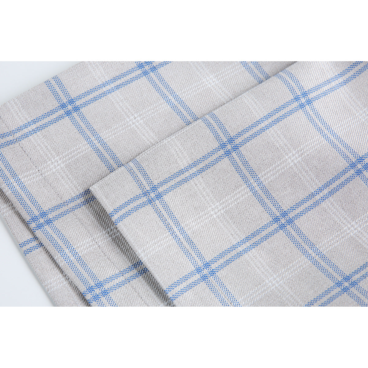Close-up of gray fabric with a blue plaid pattern and a folded seam.
