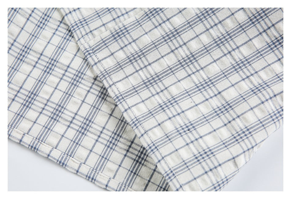 Close-up of a folded section and stitched edge of a blue-gray plaid shirt.