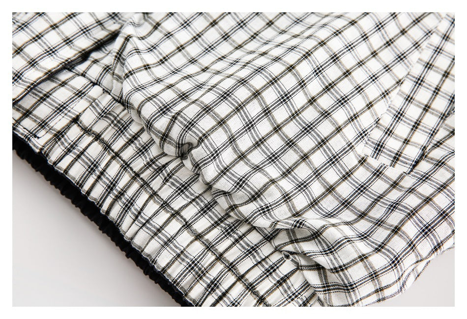 Close-up of gathered white-and-black plaid fabric along a black elastic edge.