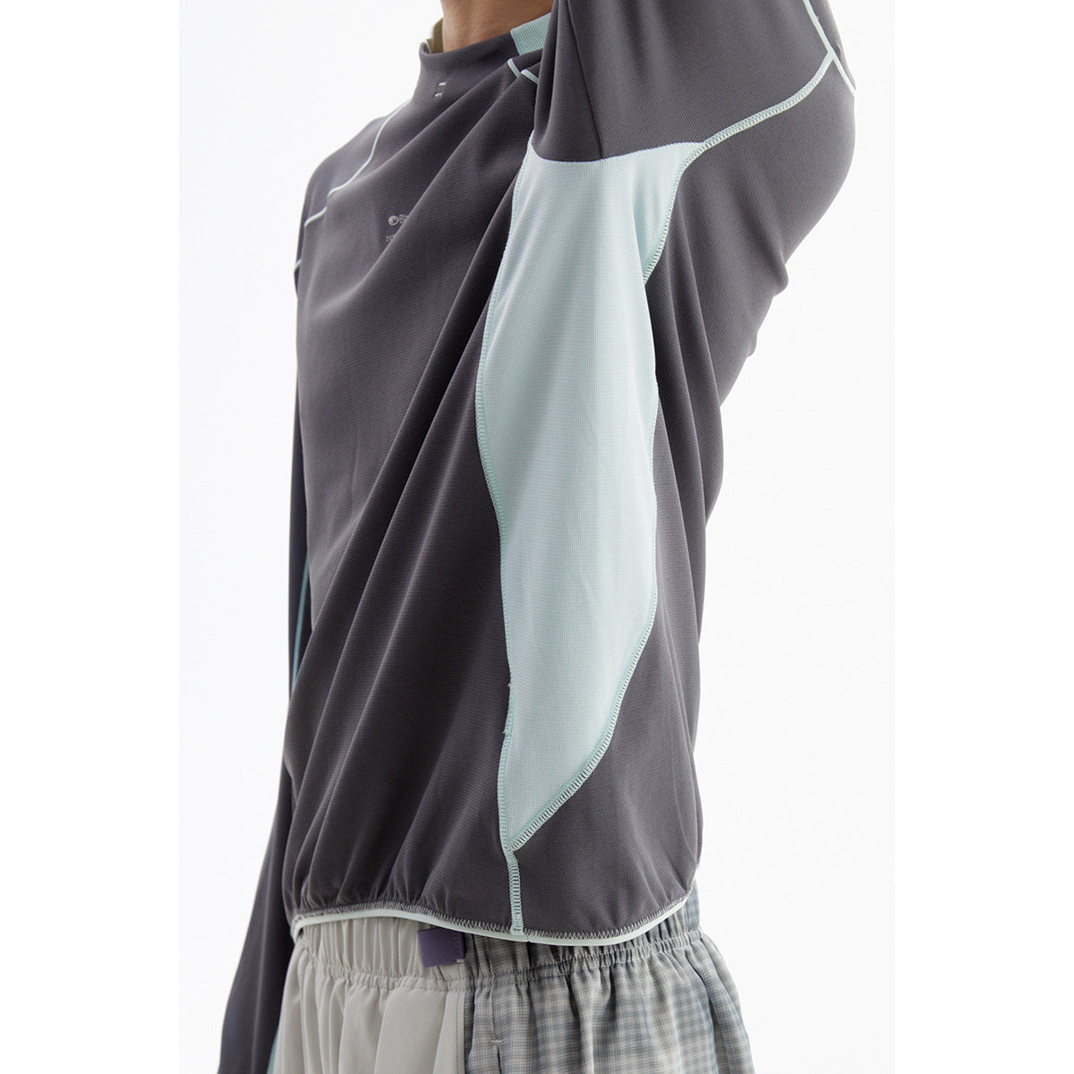 Close-up of a charcoal top's pale blue side panel, contrast stitching, and hem.