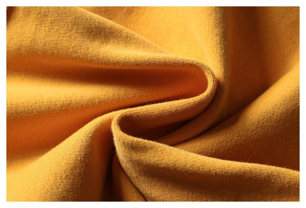 Close-up of mustard-yellow fabric draped to show its surface and folded edge.