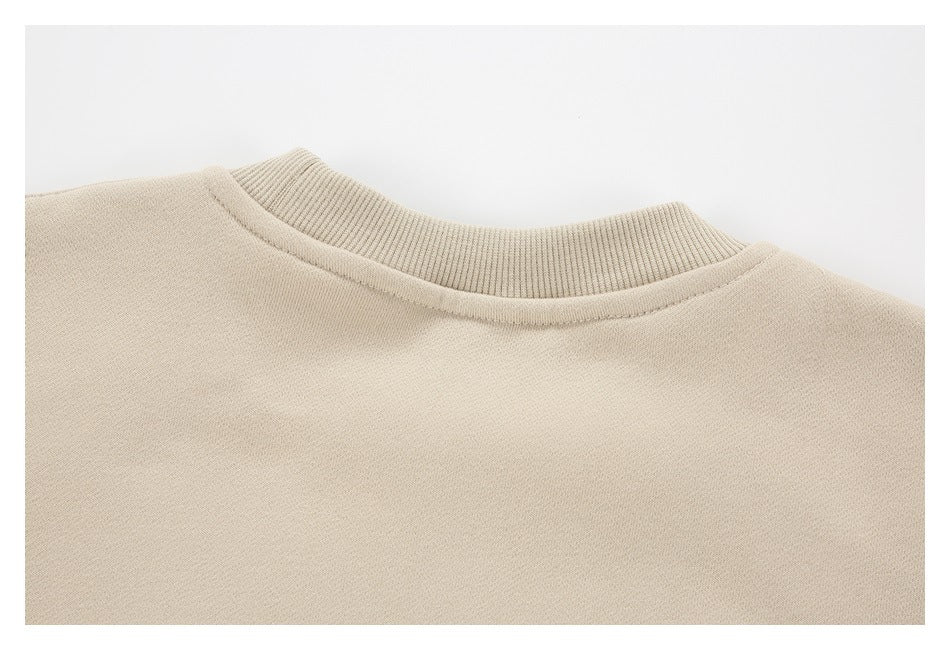 Close-up of a beige sweatshirt's round neckline with ribbed collar trim.