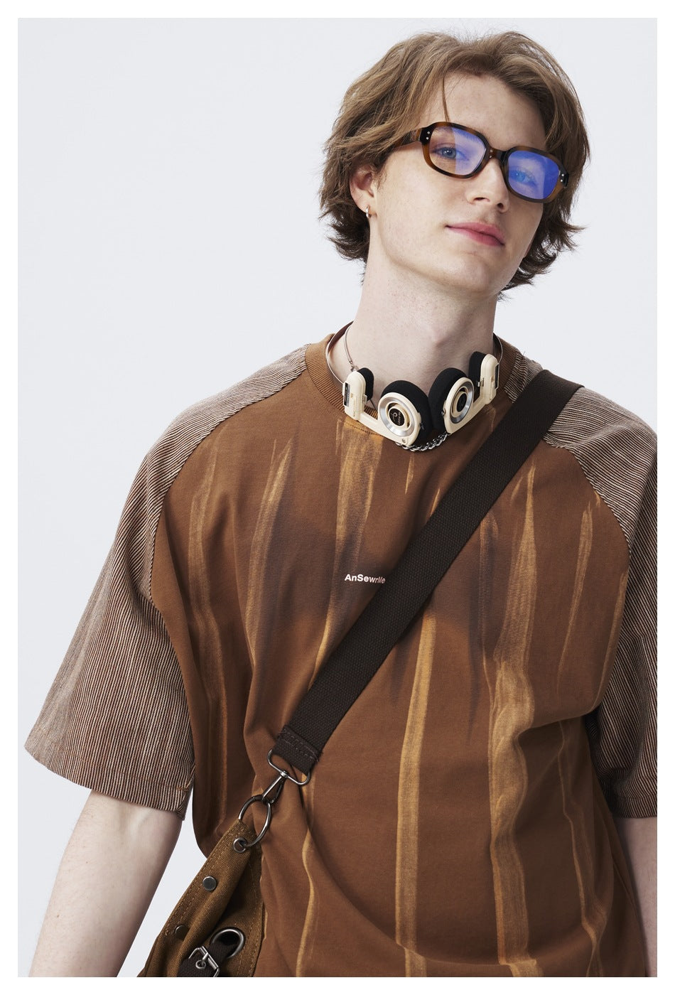 Close view of a model wearing a brown striped shirt with gray patterned sleeves and a small chest print.