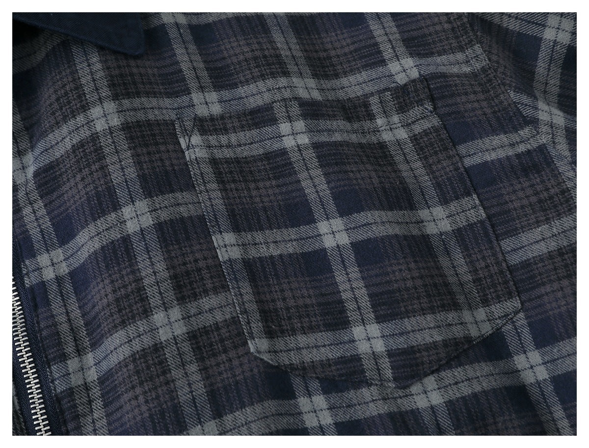 Close-up of a dark navy and gray plaid jacket pocket beside a silver zipper.