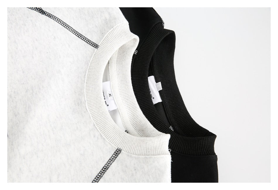Close-up of the ribbed collars and contrast stitching on light gray and black sweatshirts.