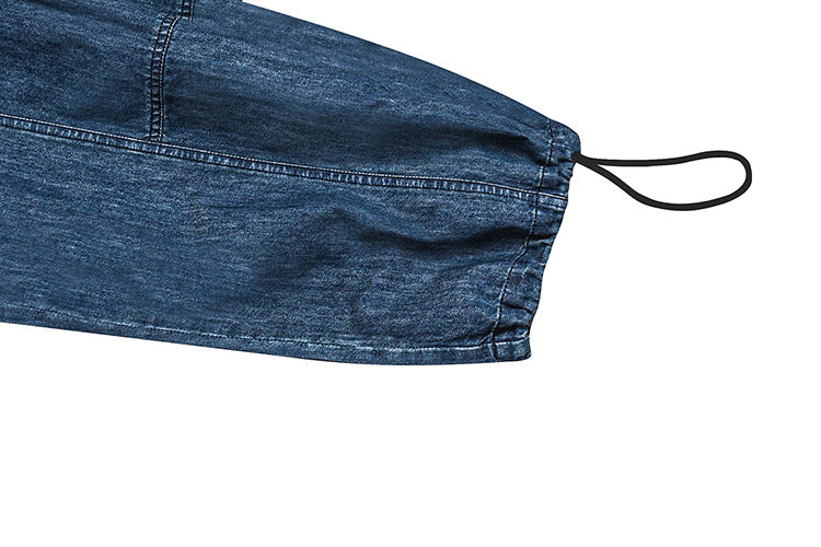 Close-up of a blue denim garment hem with visible stitching and a black elastic loop.