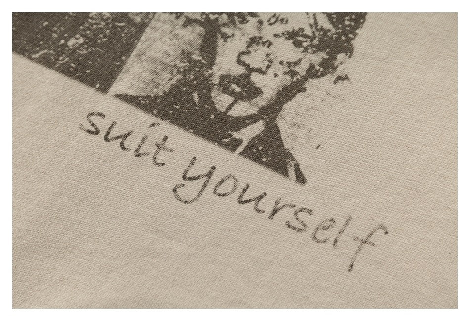 Close-up of distressed English lettering printed below a portrait graphic on beige fabric.