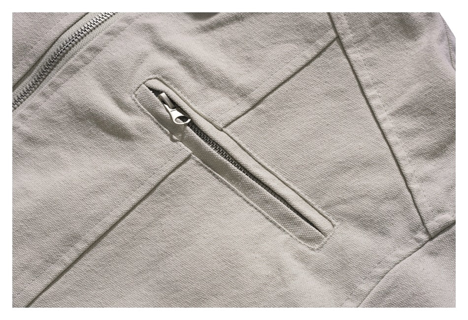 Close-up of a light gray jacket with a diagonal zip pocket and visible zipper hardware.