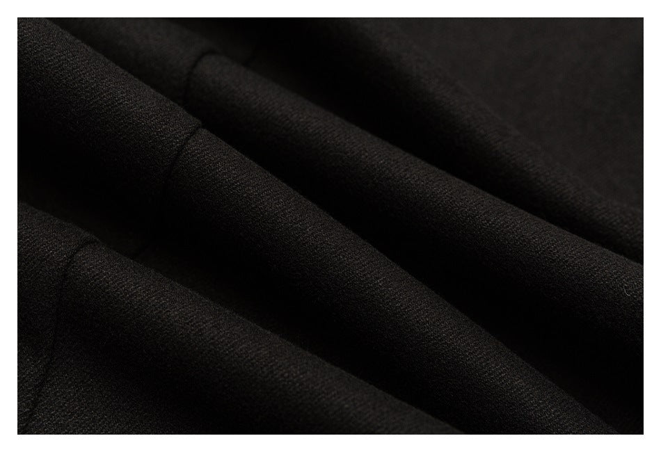 Close-up of dark charcoal trouser fabric arranged in soft folds.