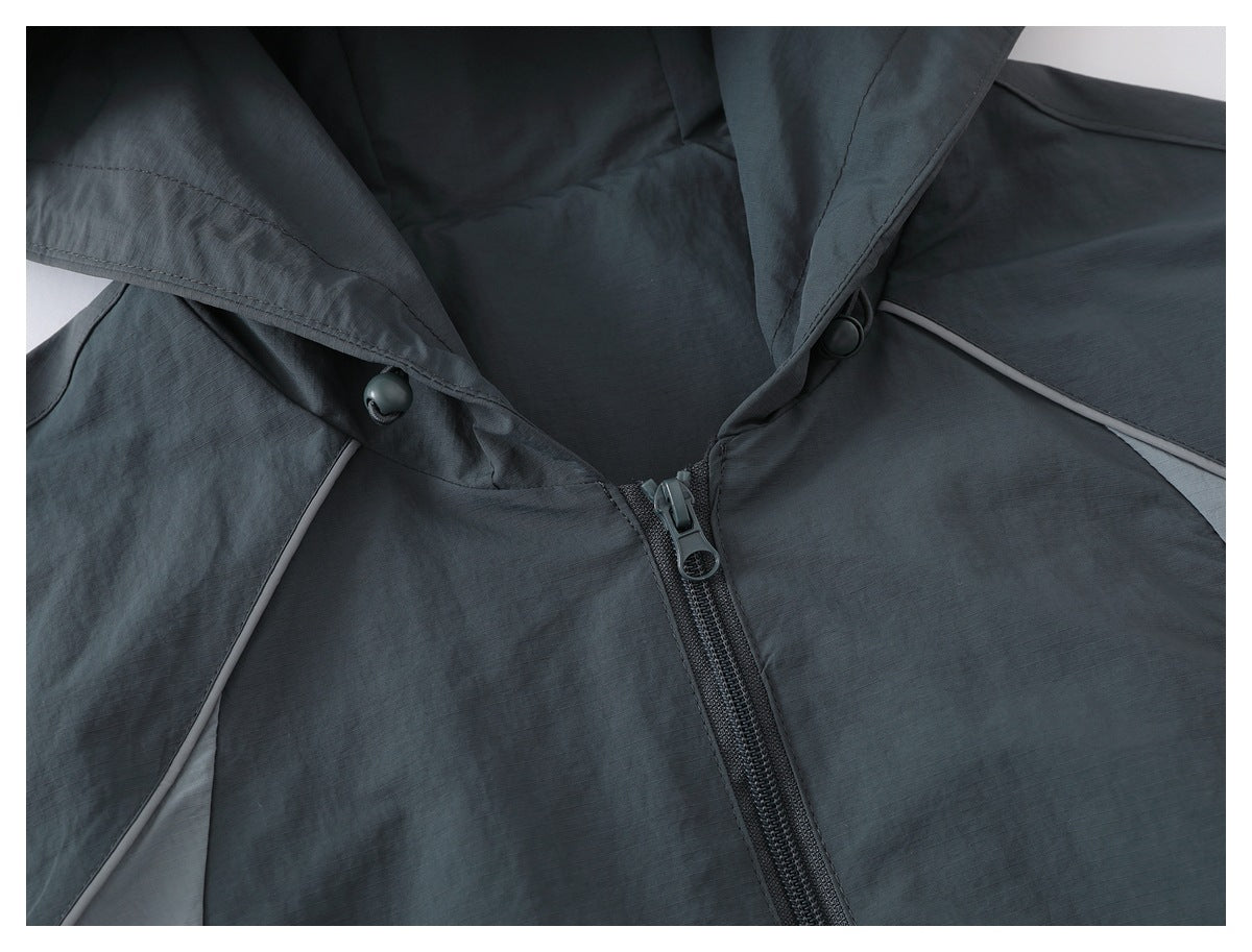 Close-up of a charcoal gray jacket's hood opening, center zipper, and light gray shoulder piping.